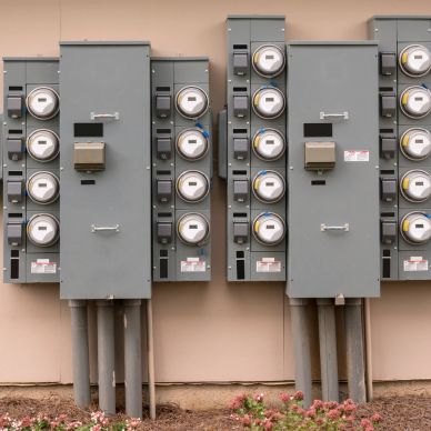 Multiple electric meters mounted on a wall.