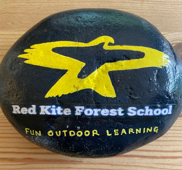 Painted rock with Red Kite Forest School logo and slogan for outdoor learning.
