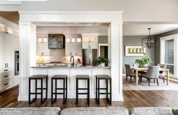 Modern kitchen with four stools and adjacent dining area.