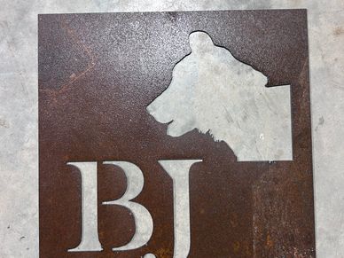 Rusty metal sheet with cut-out letters and a dog silhouette.