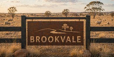 Rustic Brookvale sign on a wooden fence in a dry rural landscape.