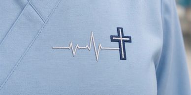 Heartbeat line morphing into a cross embroidered on fabric.