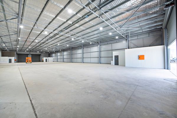 Spacious, empty warehouse with high ceilings and bright lighting.