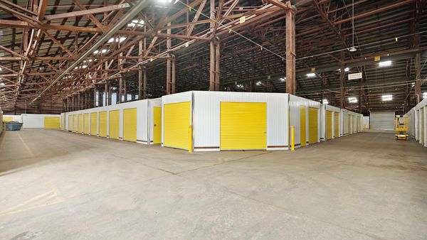 Indoor storage facility with yellow roll-up doors and high ceilings.