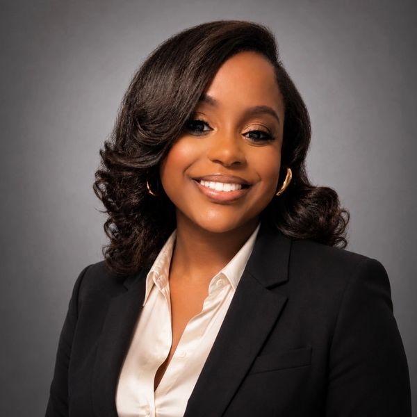 Smiling professional woman in a black blazer and white blouse.