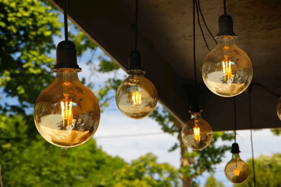 Mood-setting exterior pendant lighting above dining table in entertaining backyard. 