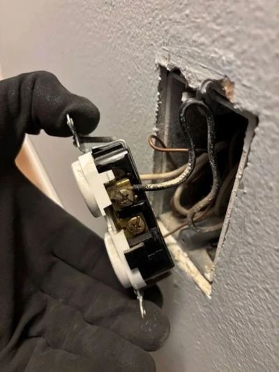 A licensed electrician working at a breaker panel to diagnose an electrical home repair. 