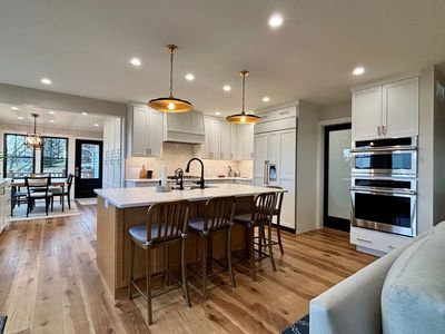 Smart lighting controls in open-concept kitchen & dining area with recessed lighting and pendants.