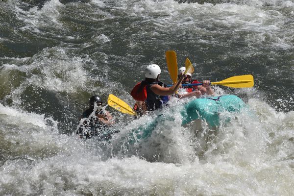 People white water rafting with yellow paddles.