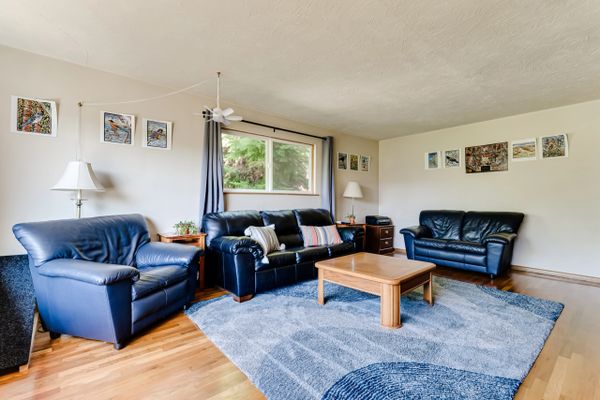 Spacious living room with blue leather sofas and wooden coffee table.