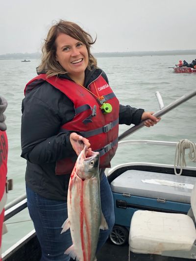 Woman holding a freshly caught fish on a boat, smiling.