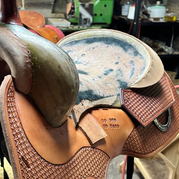Close-up of a worn Western horse saddle in a workshop.