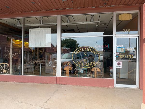 Storefront of a saddle shop with signage and window displays.