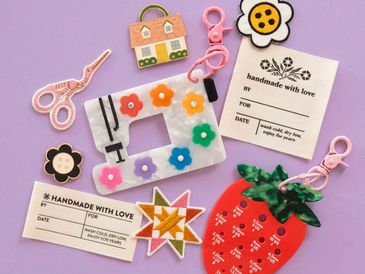 Colorful handmade keychains and tags on a purple background.