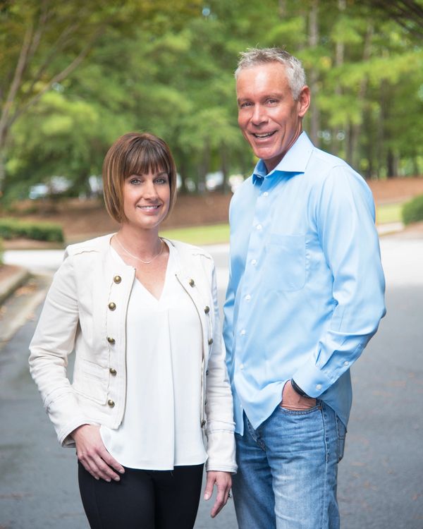 Smiling man and woman standing outdoors on a road.