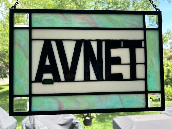 Stained glass window with the word 'AVNET' in bold black letters.