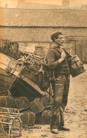 A fisherman carrying a basket and standing by lobster traps near a boat.