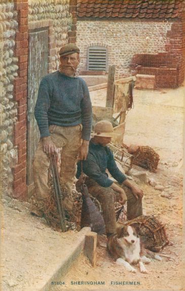 Two fishermen with their dog outside a brick building in Sheringham.