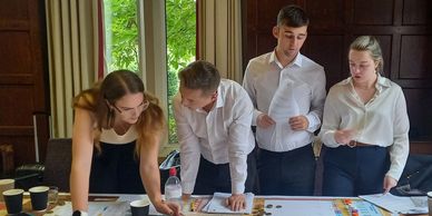 Four young professionals collaborating over documents at a meeting table.
