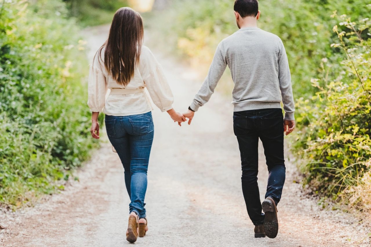 Couple walking on dirt road in forested area