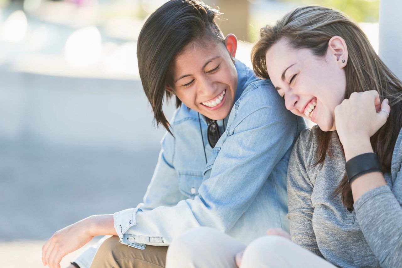 Lesbian couple laughing and leaning into one another