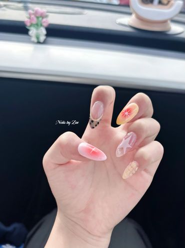 Creative nail art with stars, polka dots, and gradient colors on almond-shaped nails.