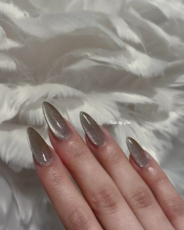 Shimmery silver stiletto nails on soft white feathers.