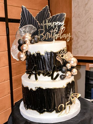 Elegant black and white birthday cake with gold accents.