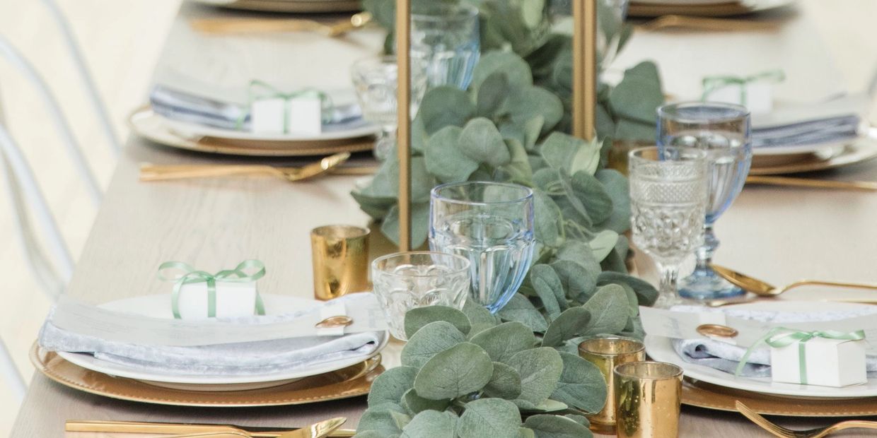 Elegant table setting with greenery and gold accents.