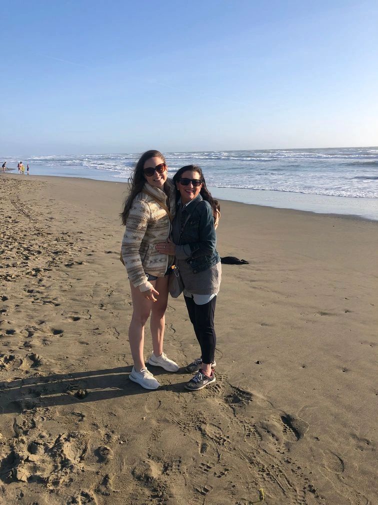 Two young woman posing for a picture near the beach