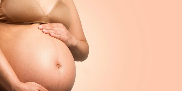 Pregnant lady holding her tummy to be massaged in a loving manner 