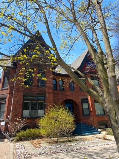 Historic red brick house with blue steps and budding tree in spring.