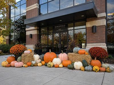 Autumn pumpkin and gourd display outside an office building entrance.