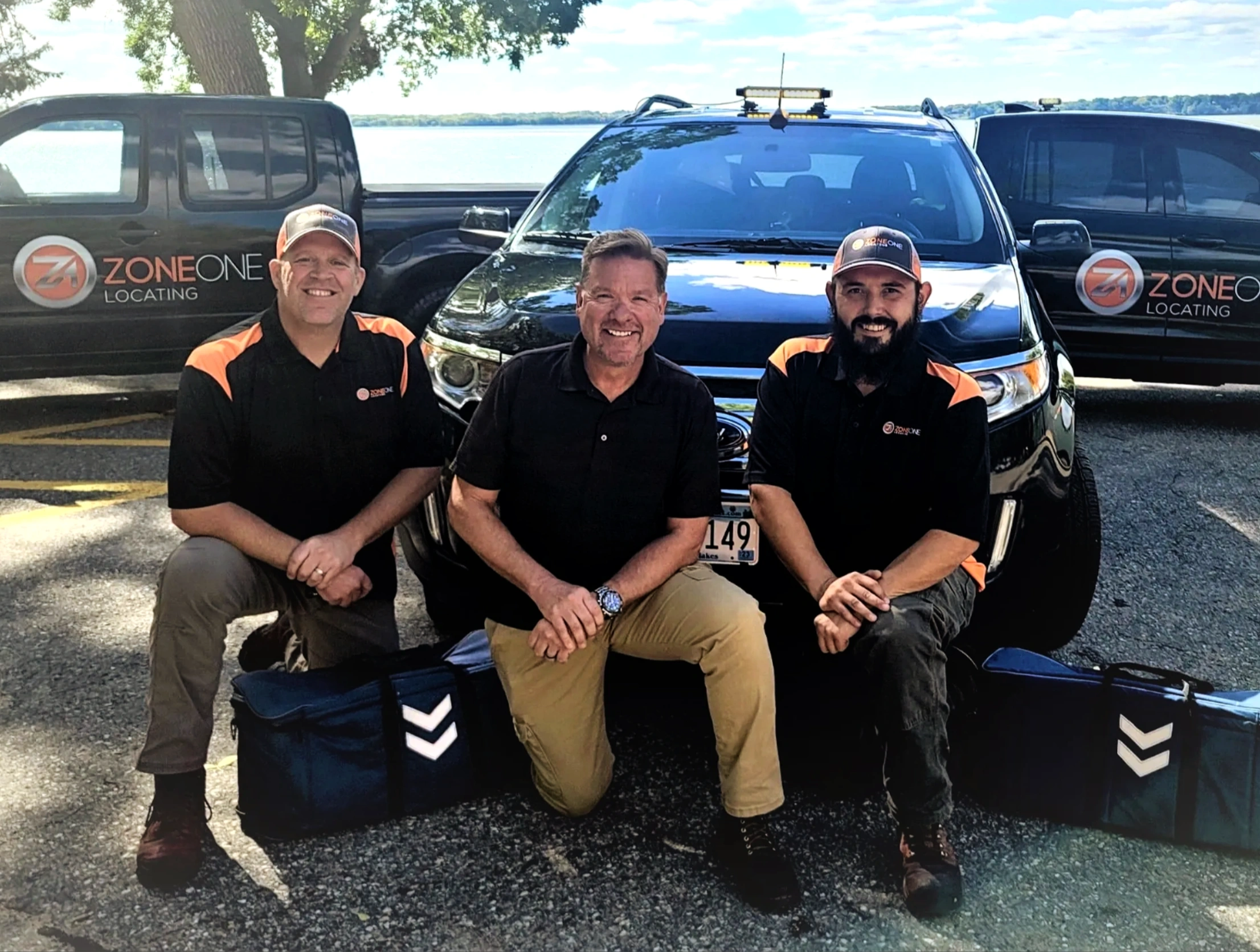 Utility locating techs kneeling in front of vehicles.