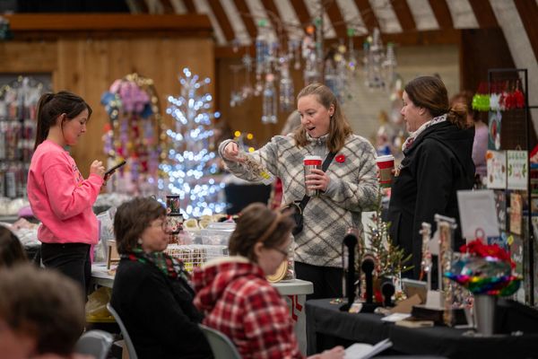 Women shopping at an indoor holiday market with festive decorations.