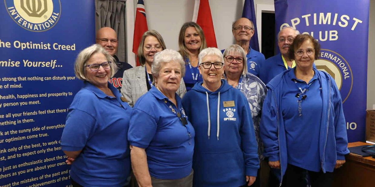 Group photo of Optimist Club members in blue shirts posing indoors.