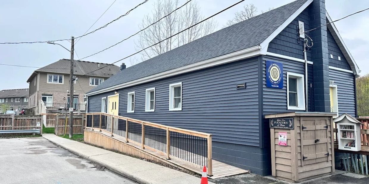 Blue building with ramp and small library box outside on a cloudy day.