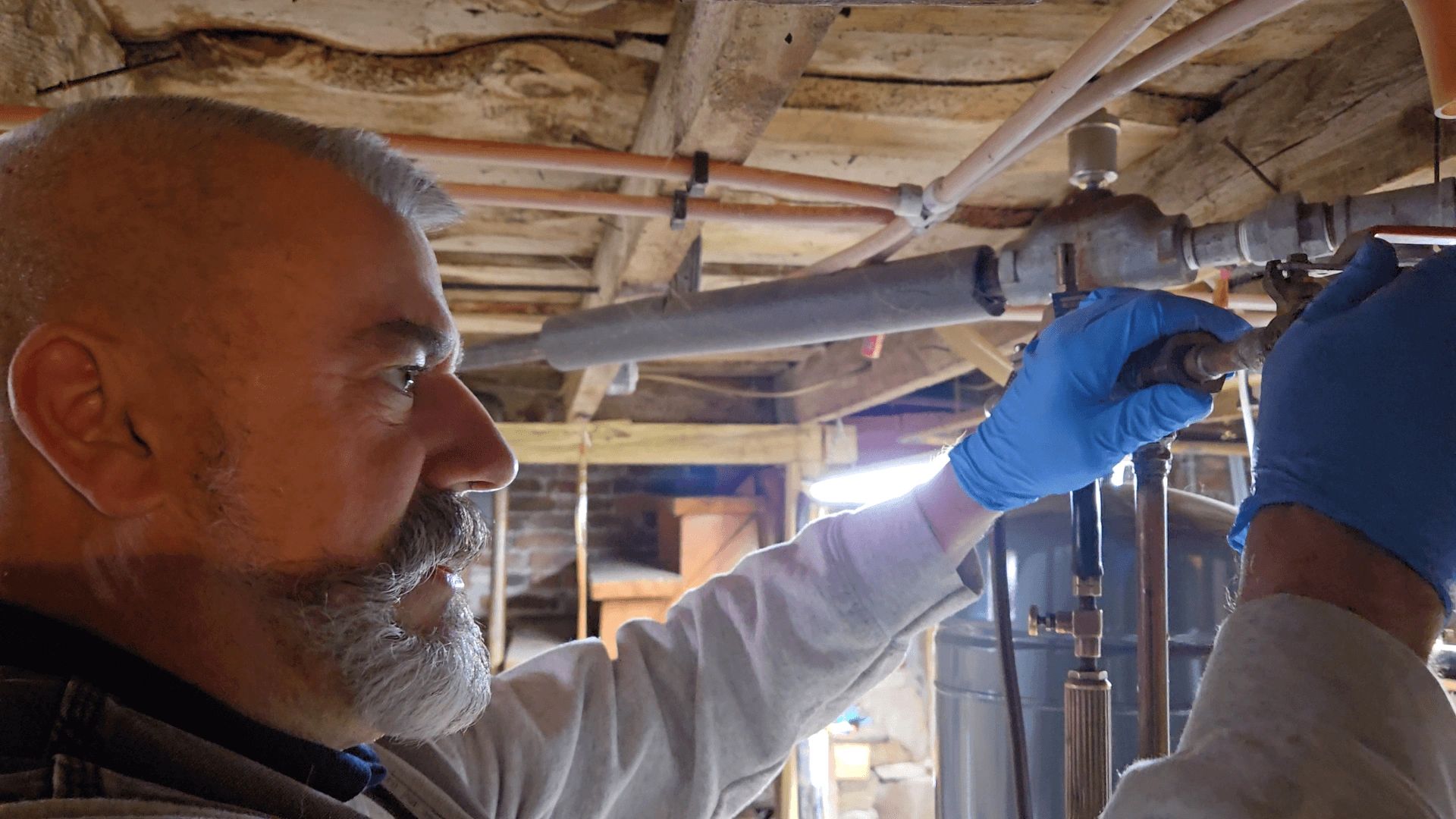 Liberty Plumbing technician working on water pipes in an Ellington, CT basement