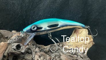 Teal and silver fishing lure named Tealtop Candy on driftwood.