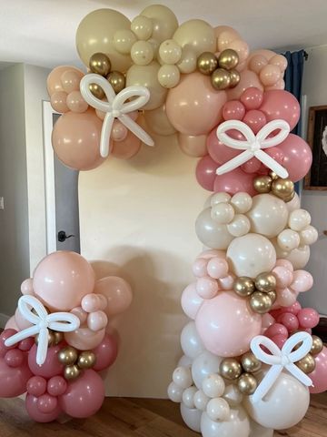 Elegant balloon arch with pastel colors and white balloon bows for decoration.