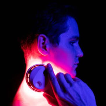 Person using a device on their neck under blue and red lighting.