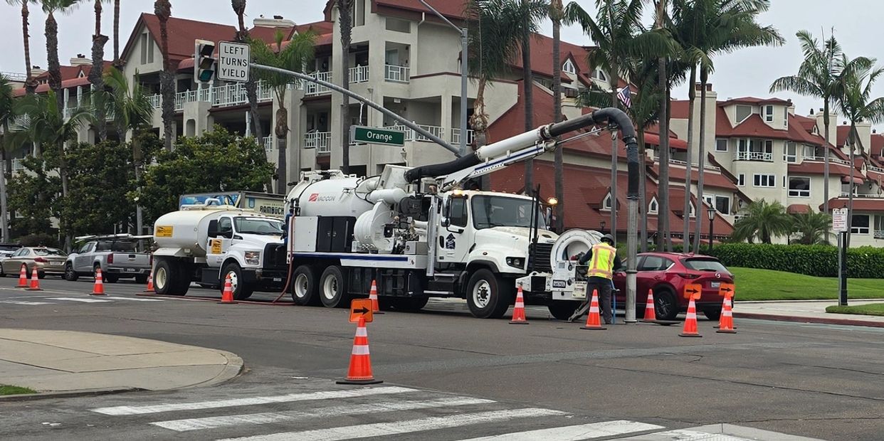 Worker using a jet vac truck and water truck to clean large diameter sewer pipe.