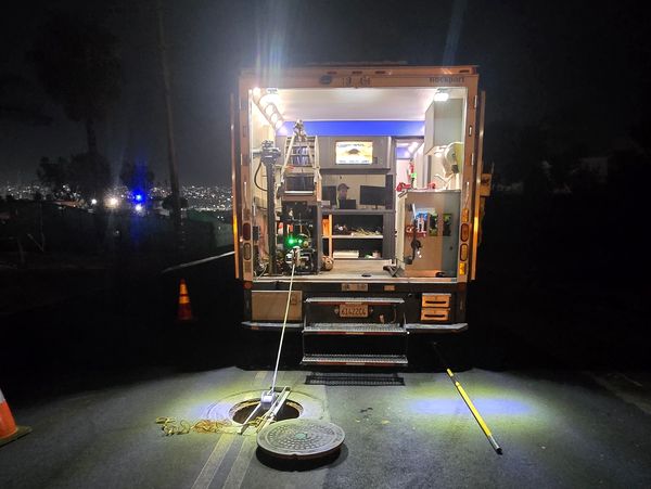 CCTV pipeline inspection van working at night with lights on. 