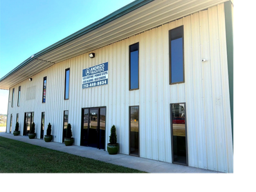 Exterior of a beige commercial building with narrow windows and a company sign.