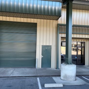 Small door next to large garage door on industrial building.