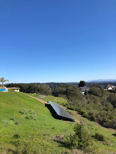 Landscape view of hill-side solar installation on a residential property. Solar panel installation d