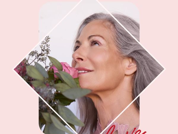 Elegant older woman smelling a bouquet of pink flowers with a serene smile.