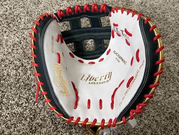 A black, white, and red Liberty Advanced baseball catcher's mitt on carpet.
