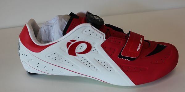 Red and white cycling shoe with Velcro strap and dial closure.