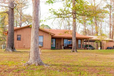 A wooden house surrounded by trees in a peaceful yard.